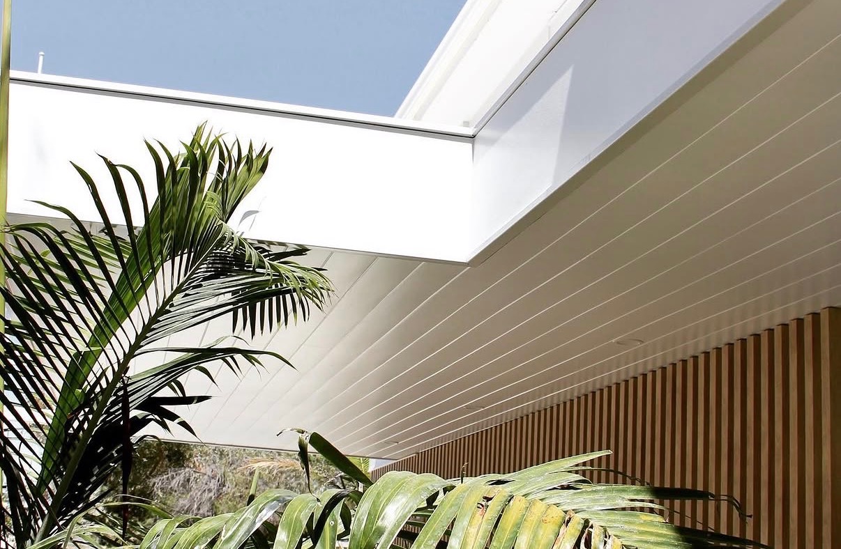 Crisp white painted soffit and fascia above timber battens and palms