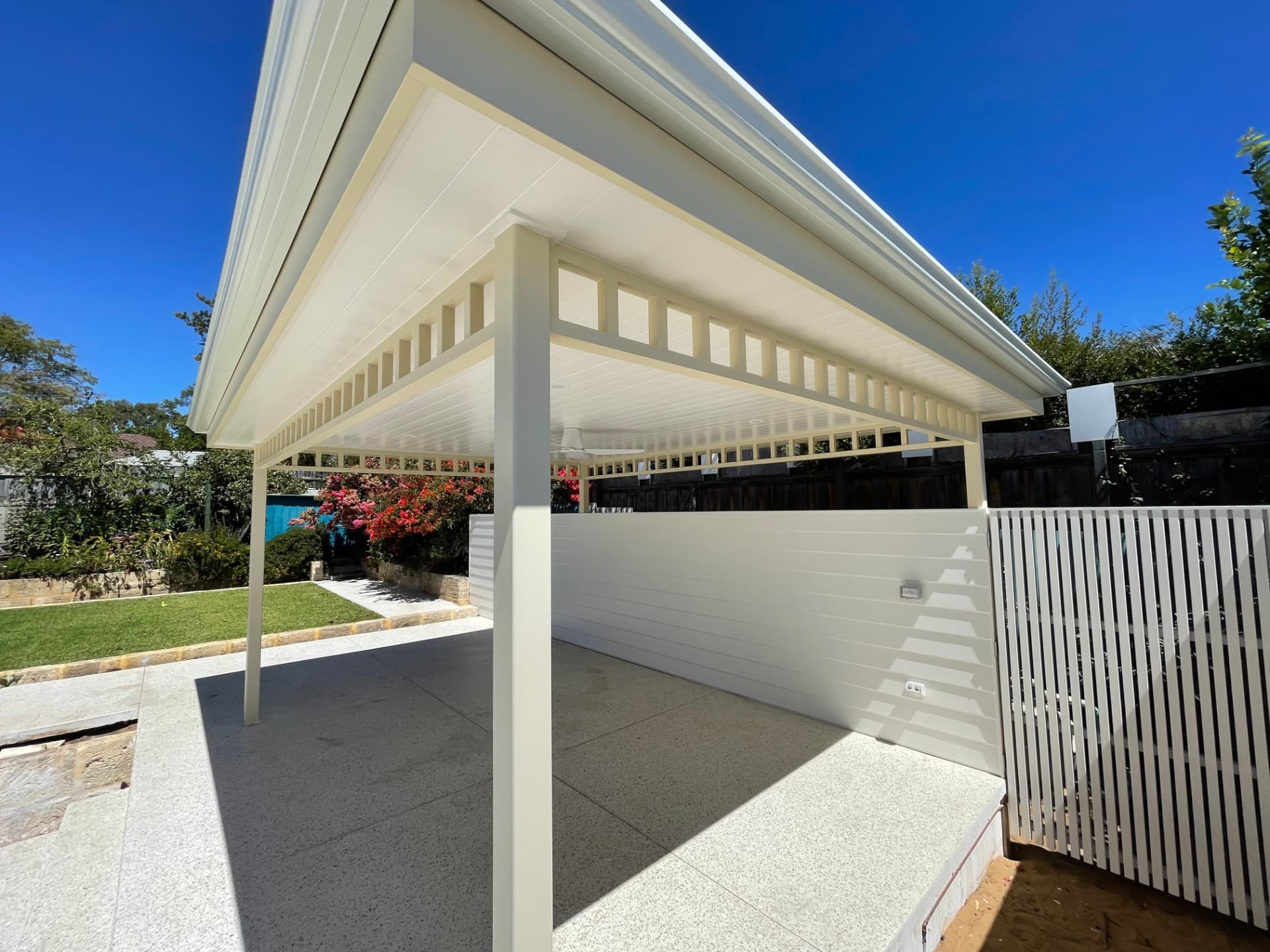 Pavilion and white slat fence painted against lawn and garden beds